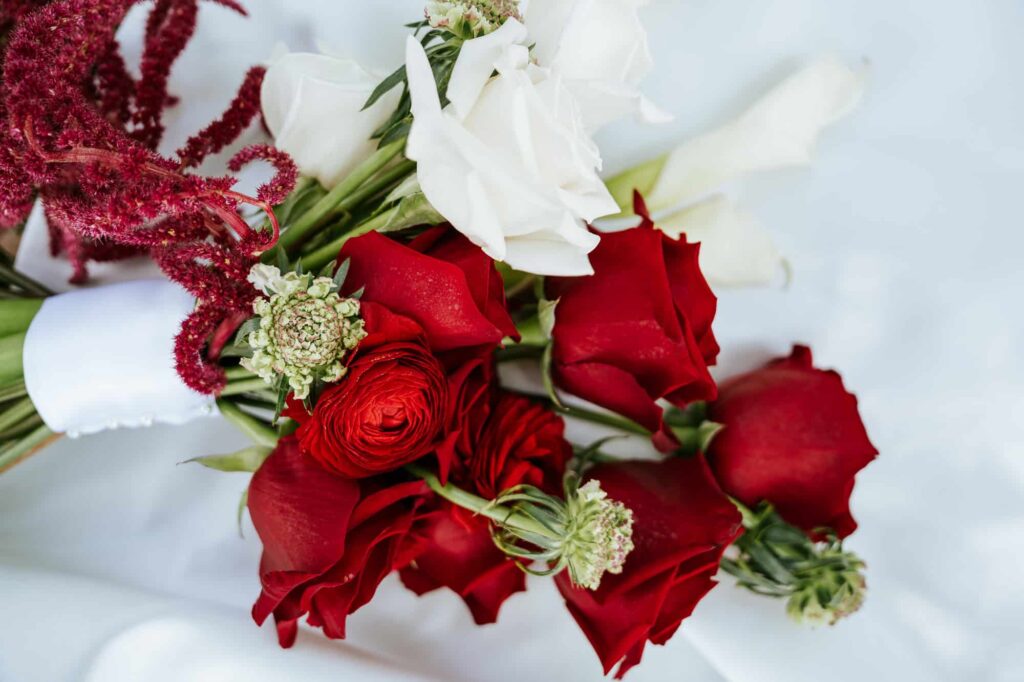 Red and white wedding rose bouquet laying on the train of a white wedding dress at Magnolia building wedding in Lakeland Florida