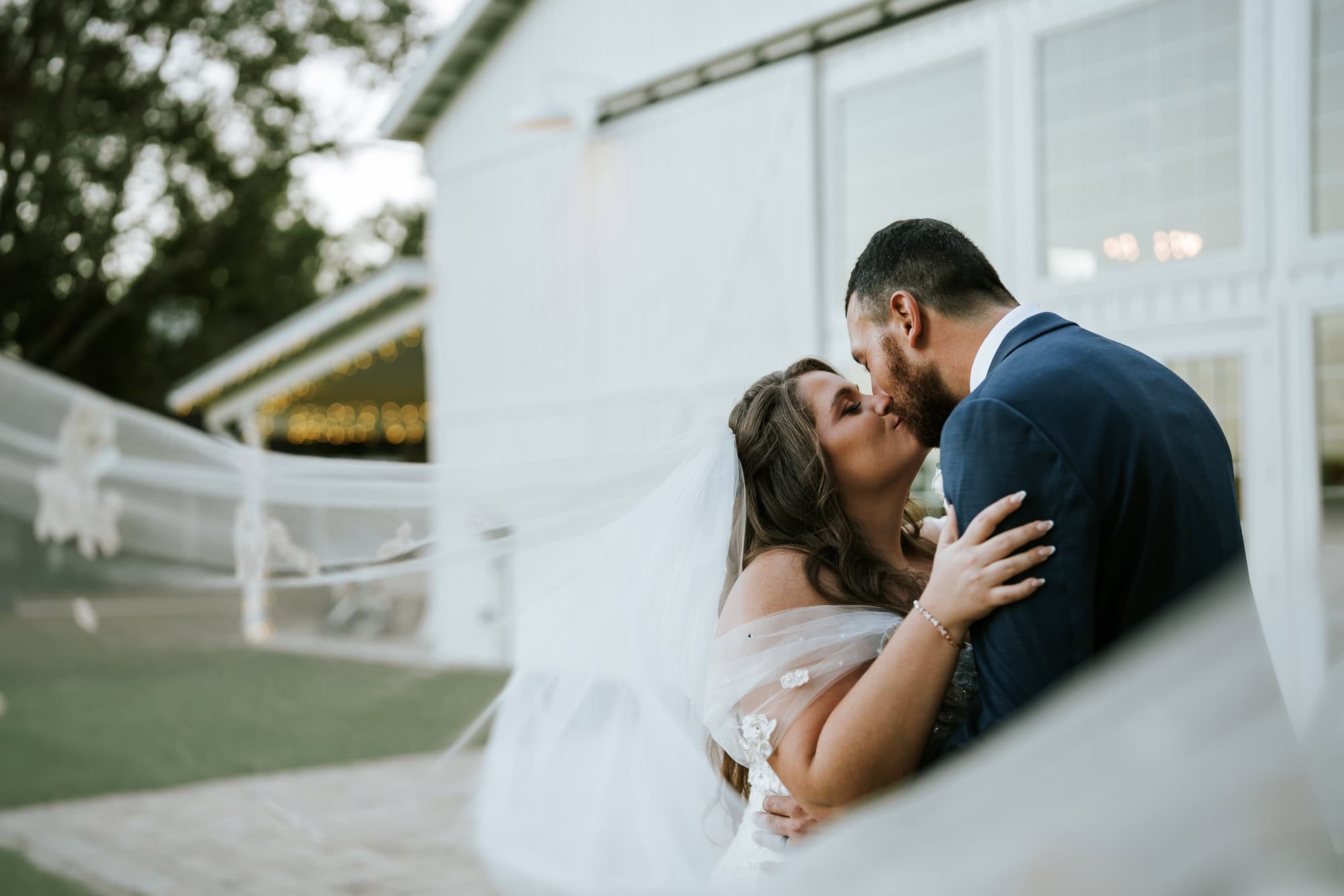 veil shot of the newlyweds in front of their barn wedding venue