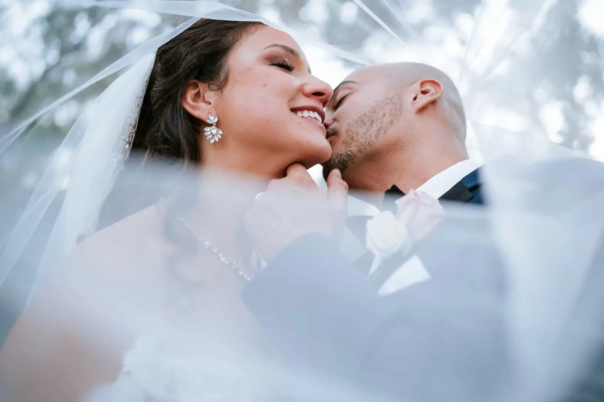 Groom kisses his bride under the vail at their Bakers Ranch wedding venue in Tampa, Florida. Captured by Peachstate Weddings Atlanta Photographer