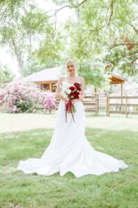 Lucy in her timeless white wedding gown holding her wedding bouquet with red and white roses. Captured by Peach State Weddings - Florida Destination Wedding Photographer