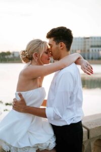 Dreamy, sun-drenched wedding portraits of a couple standing on the edge of Lake Mirror; captured by Peach State Weddings.
