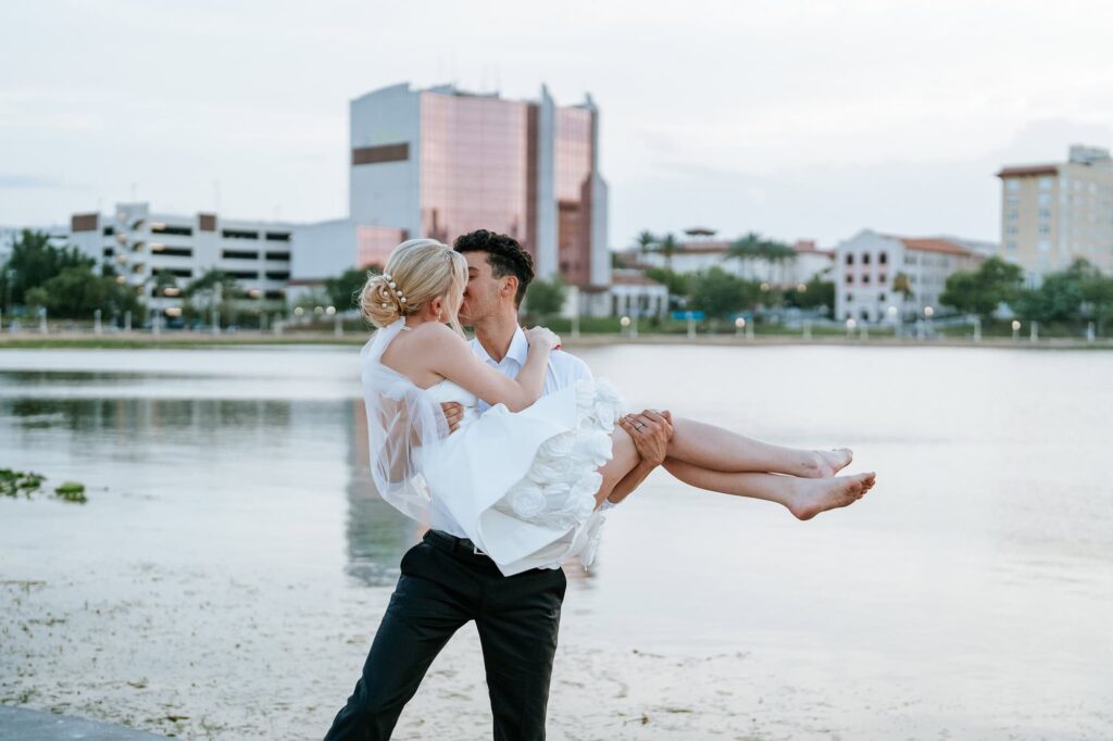 Sunset wedding photos on the shores of Lake Mirror, featuring the reflection of the Lakeland skyline in the water at dusk.
