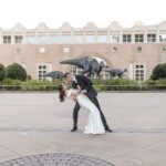 Everything You Need to Know About the Fernbank Museum Wedding Venue 7 Groom is dipping his bride during sunset portraits in front of the Fernbank museum, a premier wedding venue in Georgia captured by Atlanta wedding photographer Peach State Weddings