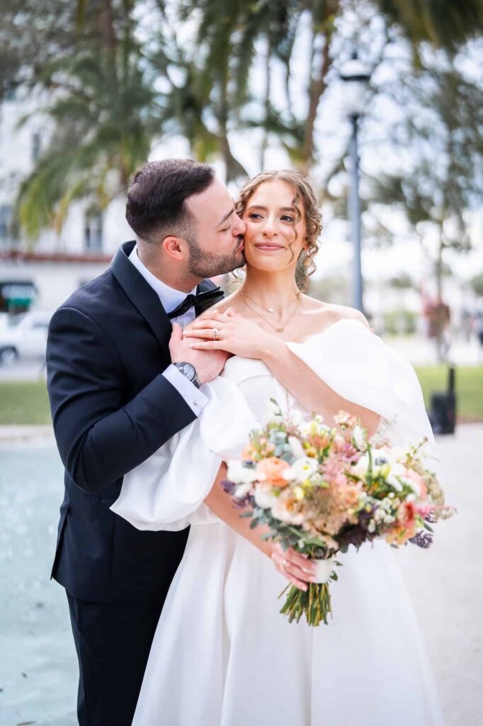 Jewish groom kisses his bride on the cheek after their first look in front of Casa Monica Resort in North Florida 