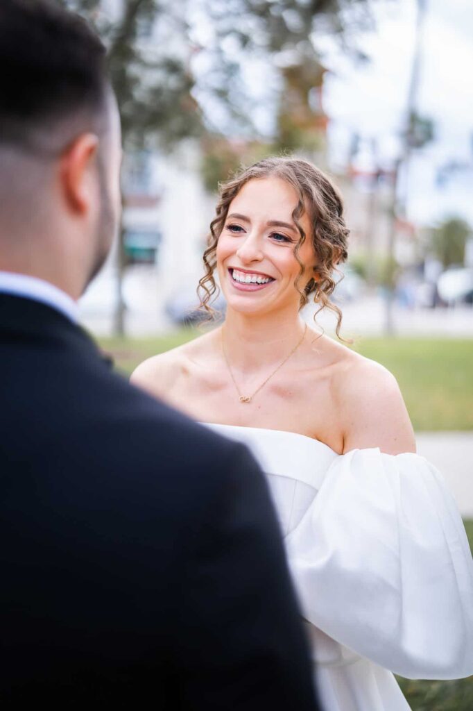 A jewish bride with curly hair smiles radiantly at her groom during an Atlanta destination wedding at Casa Monica.