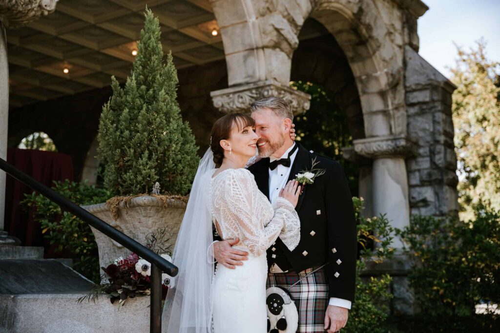 Romantic wedding couple posing near the Stone Mountain granite arches of Rhodes Hall; captured by Peach State Weddings.