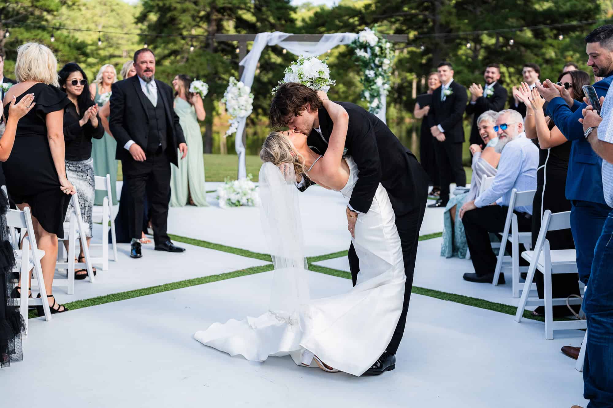 Groom dips the bride in the middle of the aisle and kisses her - one epic moment captured by Peach State Wedding photographer in South Georgia at The Venue at Daisy Hill