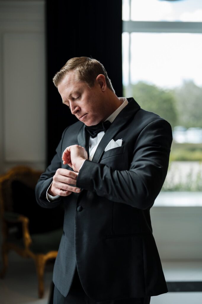 A candid shot of a groom adjusting his tuxedo cufflinks while getting ready for a wedding at the World Equestrian Center in Ocala, Florida.