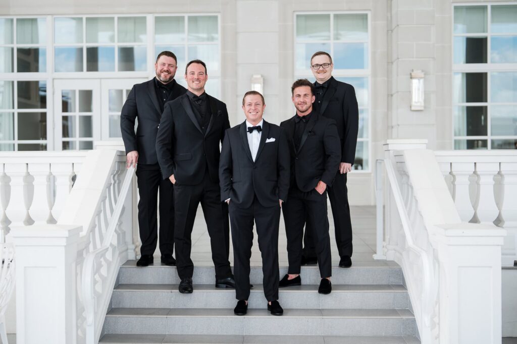tlanta Georgia wedding photographer captures a groom and his groomsmen in black tuxedos standing on the white steps of the World Equestrian Center.