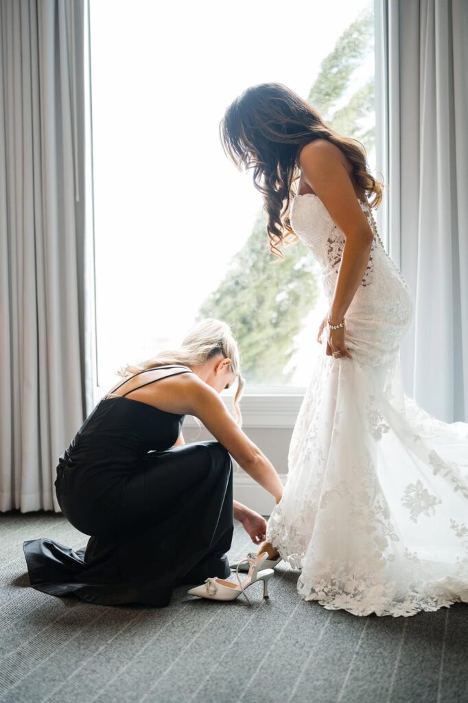 Bridesmaid is helping the bride putting her shows on at a world equestrian center wedding in Ocala captured by Atlanta Wedding Photographer Peach State Weddings