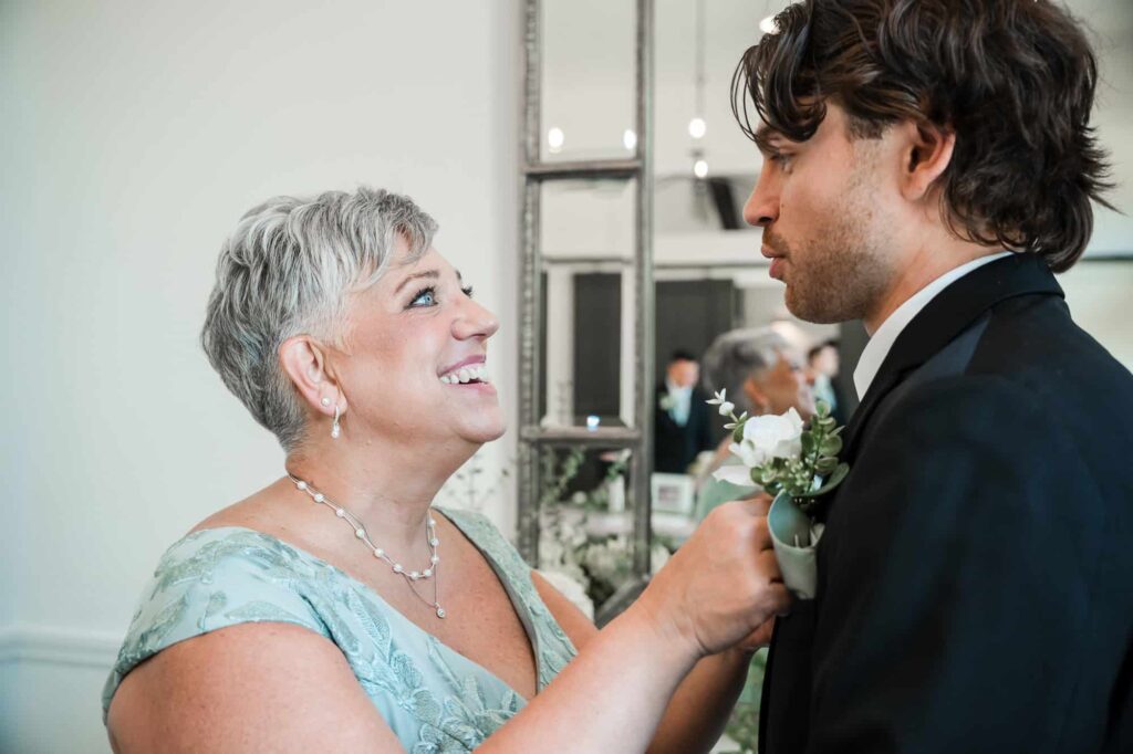 Fayetteville photographer capturing the groom's mother pinning the boutonniere on her son just moments before the wedding ceremony at the venue at daisy hill