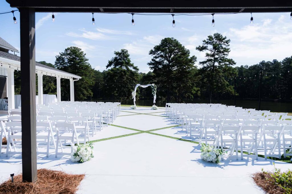 Wide shot of the outdoor wedding ceremony at The Venue at Daisy Hill in Fayetteville, Georgia, featuring the lakeside pergola.