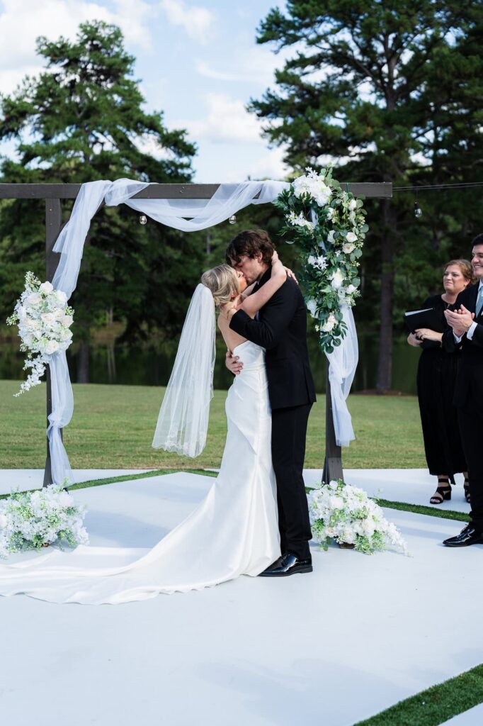 The first kiss of Hannah and Zach during their outdoor wedding ceremony at The Venue at Daisy Hill; captured by Peach State Weddings.