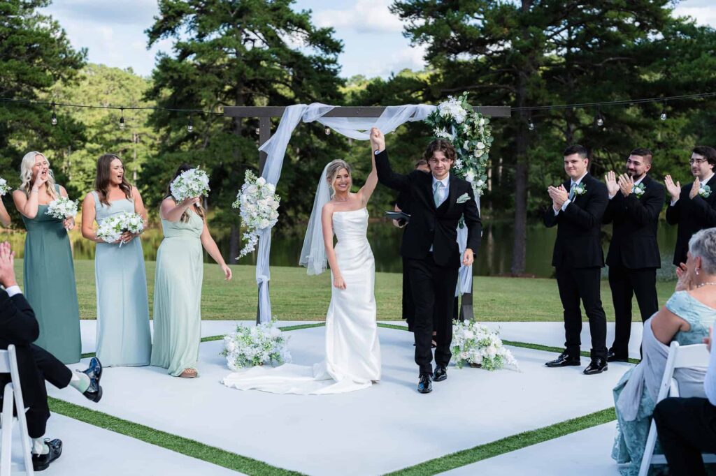 Joyful bride and groom walking back up the aisle as husband and wife at a lakeside Fayetteville wedding.
